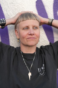 a woman leaning against a wall with graffiti on it