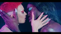 two women kissing each other in front of a neon light
